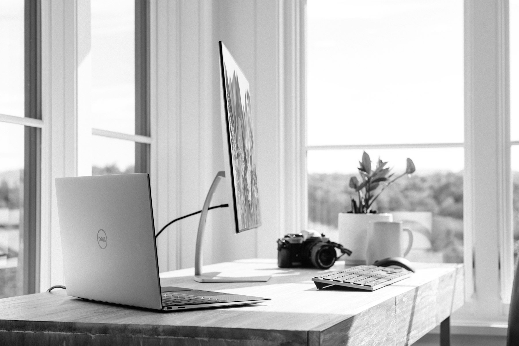 Bureau lumineux avec ordinateur portable et écran près d'une fenêtre